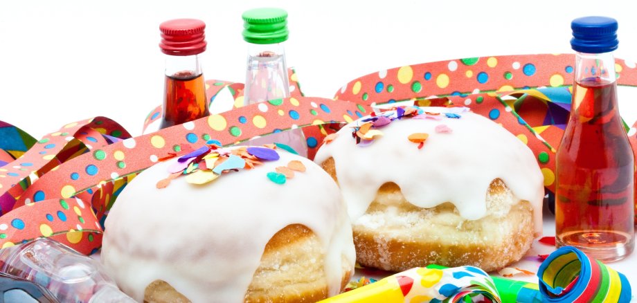 Berliner mit Zuckerguss, Likörflaschen und Tröten auf Konfetti